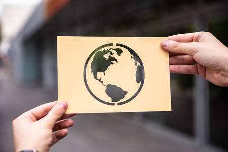 Hands Holding Paper With Cutout Planet Earth Outdoorsの写真素材