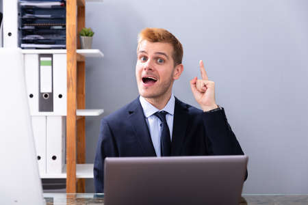 Businessman Having Ah Ha Moment While Working In Office On Laptopの写真素材