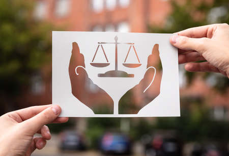 Hands Holding Paper With Cutout Hands Protecting Scales Outdoorsの写真素材