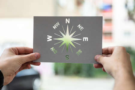 Hands Holding Paper With Cutout Compass Outdoorsの写真素材