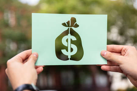 Hands Holding Paper With Cutout Money Sack Outdoorsの写真素材
