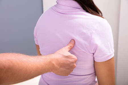 Close-up Of A Male Physiotherapist Giving Back Massage To Female Patient Sitting In Clinic
