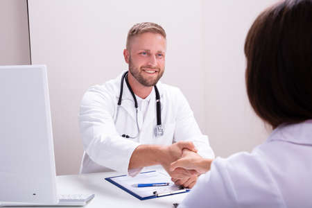 Male Doctor Shaking Hands With Female Nurse In Clinicの写真素材