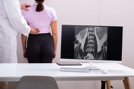 Male Doctor Therapist Treating Lower Back Pain Of Female Patient In Clinicの写真素材
