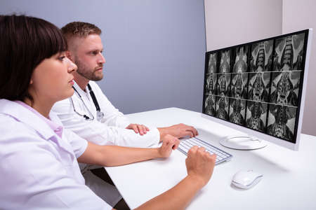 Doctors Looking At An MRI Scan At Computer In Clinic
