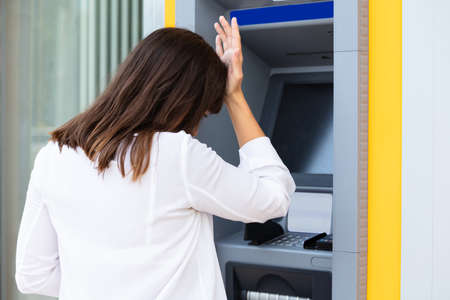 Close-up Of Disappointed Young Woman Looking At ATM Bank Machine After Checking The Account Balanceの写真素材