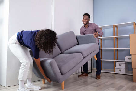 Couple Placing Sofa In New Living Roomの写真素材