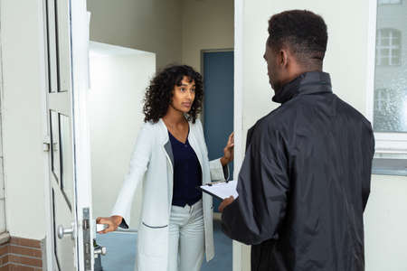 Stressed Woman Opening Door To Bailiff At Homeの写真素材