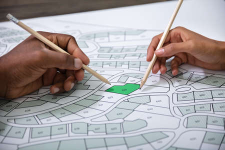 Hands Holding Pencils Over Cadastre Map Stock Photoの写真素材