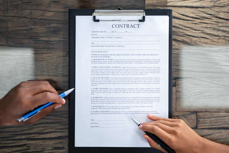 Close-up Of A Two Person's Hands Reviewing Contract Form