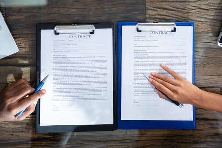 Two Businesspeople Working On Contract Paper In Office
