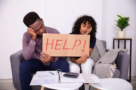Worried Couple Holding Help Sign While Calculating Billsの写真素材