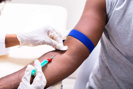 Close-up Of Doctor Taking Blood Sample From Patient's Armの写真素材