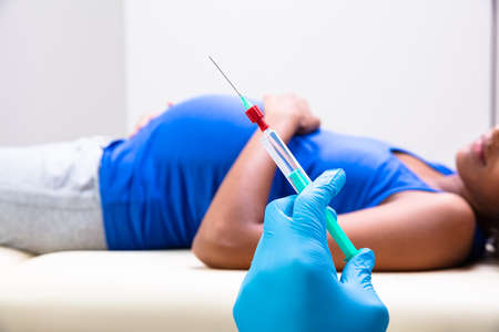 Doctor Preparing Vaccine Injection For Pregnant Woman At Clinicの写真素材