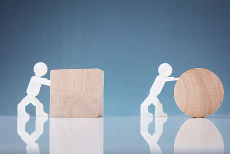 White Two Human Figure Pushing Wooden Block And Circle On Reflective Backgroundの写真素材