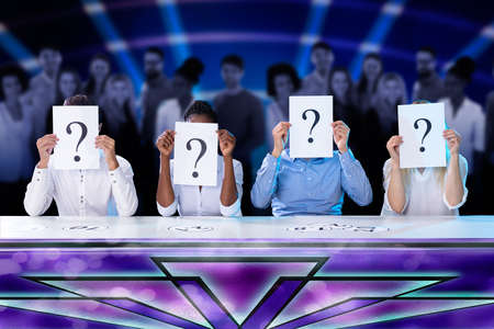 Businesspeople Sitting In Conference Room Holding Question Mark In Front Of Faceの写真素材