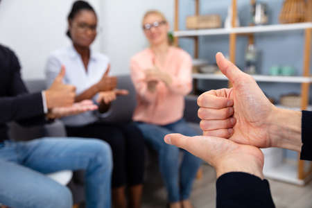 Close-up Of A Person Teaching Sign Languages To Multiethnic Pupils Sitting On Sofa At Home
