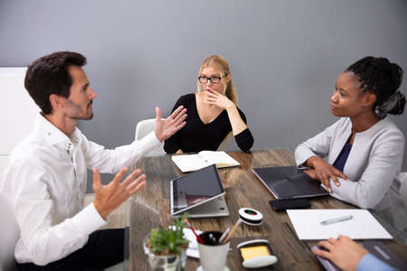 Female Colleagues Looking At Male Executive Discussing Project Plan In Meeting Room