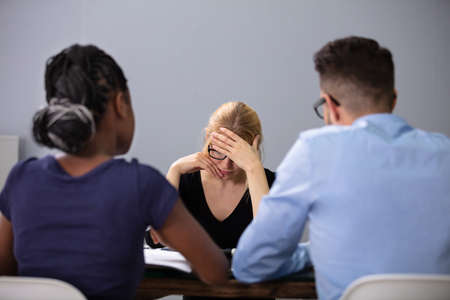 Young Unhappy Woman Sitting In Front Of Managers In Office For Interview