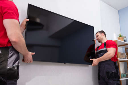 Movers Fixing The Large Flat LCD Television On Wall In The Living Roomの写真素材