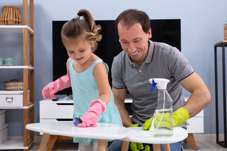 Cute Smiling Daughter Helping His Father For Cleaning The White Stool With Sponge At Homeの写真素材