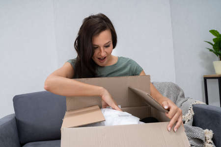 Woman's Hand Opening Delivered Parcel At Home