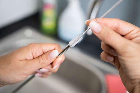 Woman Cleaning Reusable Metal Straw In Kitchenの写真素材