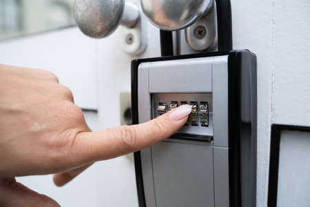 Woman Using Key Safe To Retrieve Keys From House