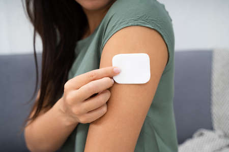 Woman Applying Patch On Her Arm At Home