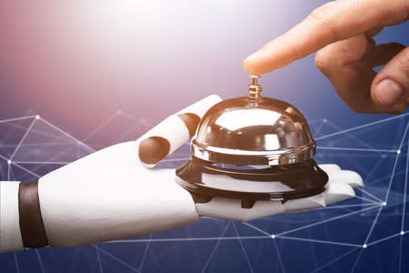 Close-up Of A Person Ringing Service Bell Hold By Robot Against Technology Background