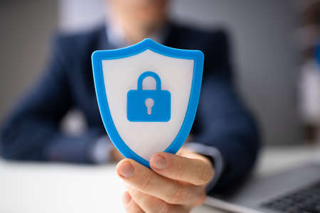 Close-up Of A Businessperson's Hand Holding Blue Shield Security Icon