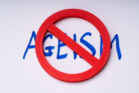 Red Stop Sign On Handwritten Ageism Text Over White Backdrop