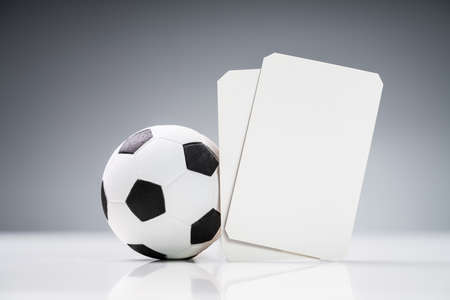 Close-up Of Miniature Basketball With White Tickets Cards And Coupons On Reflective Desk