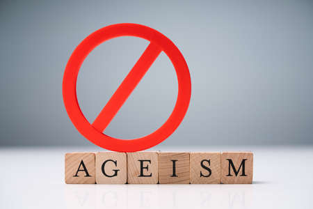 Ageism Text On Round Wooden Blocks Over Reflective White Deskの写真素材