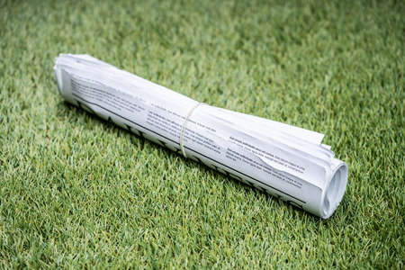 Bunch Of Newspapers Tied With Rubber Band On Green Grass At Lawnの写真素材