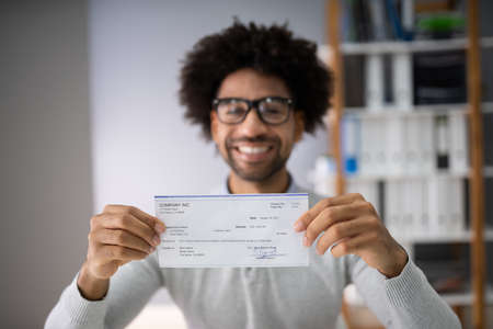 Midsection Of Smiling Businessman Holding Cheque In Officeの素材 [FY310134306753]