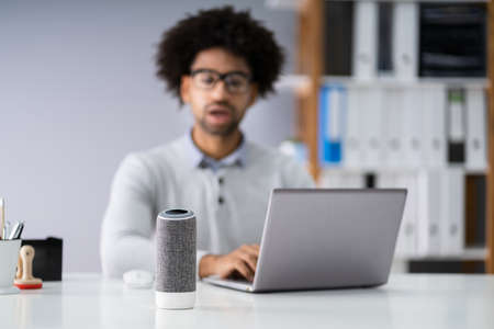 Close-up Of Young Businessman Speaking On Wireless Speaker At Workplaceの写真素材