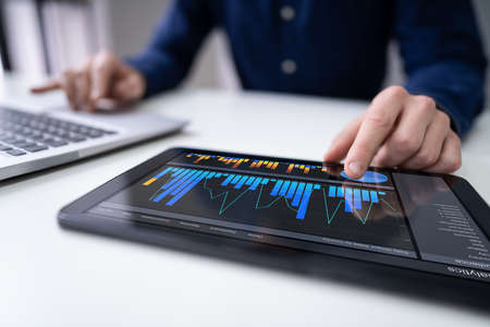 Close-up Of A Businesswoman's Hand Analyzing Graph On Digital Laptop At Workplace