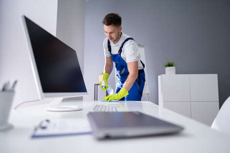 Portrait Of Happy Young Maid Cleaning Glass Table In Officeの写真素材