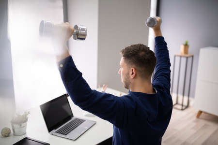 Attractive Businessman Exercising With Dumbbells In Officeの写真素材