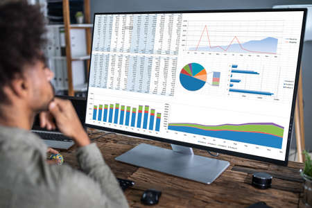 Close-up Of A Businesswoman's Hand Analyzing Graph On Computer At Workplace
