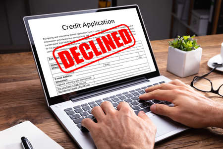 Person Typing On Laptop Keypad With Screen Showing Declined Message On Credit Application