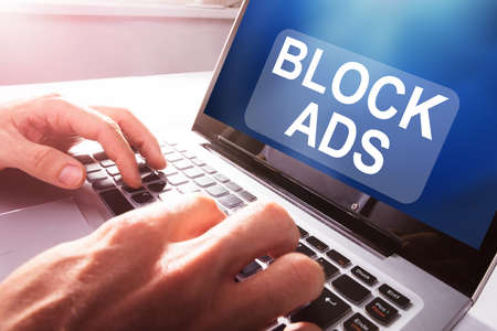 Close-up Of A Businessperson Using Laptop With Block Ads Message On Screen At Officeの写真素材