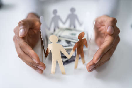 Person's Hand Protecting Stacked Banknotes Surrounded By Human Figures