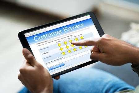 Close-up Of Person On Sofa With Digital Tablet Showing Survey Formの写真素材