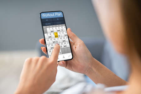 Person Hand Holding Smartphone With Workout Plan