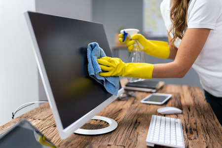Young Worker Cleaning Desk With Rag In Officeの写真素材