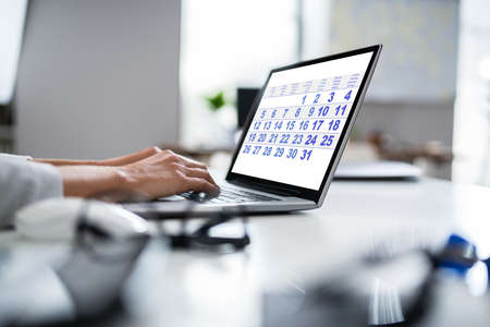 Young Businesswoman Looking At Calendar On Laptop At Deskの写真素材