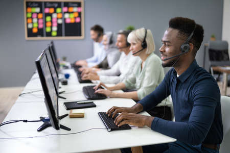 Positive Male Customer Services Agent With Headset Working In A Call Center