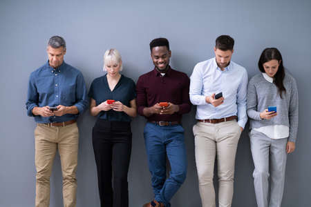 Row Of Diverse Businesspeople Using Phones In Officeの写真素材